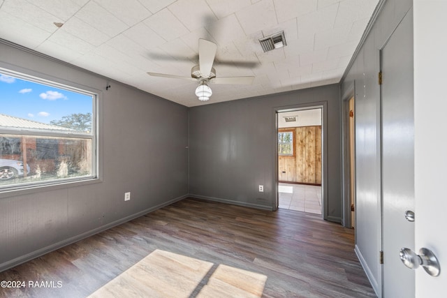 empty room with crown molding, ceiling fan, and dark wood-type flooring