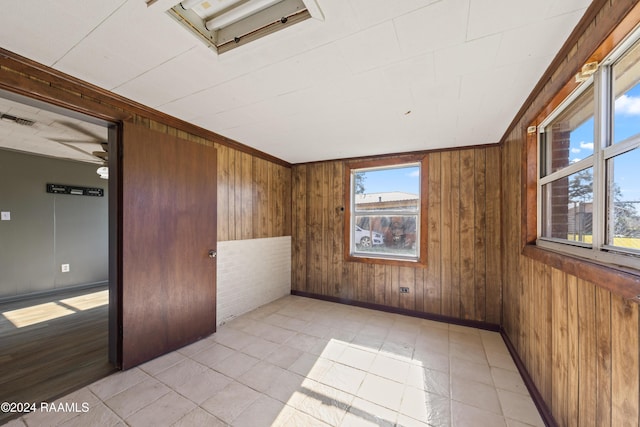 unfurnished room featuring ceiling fan and wood walls