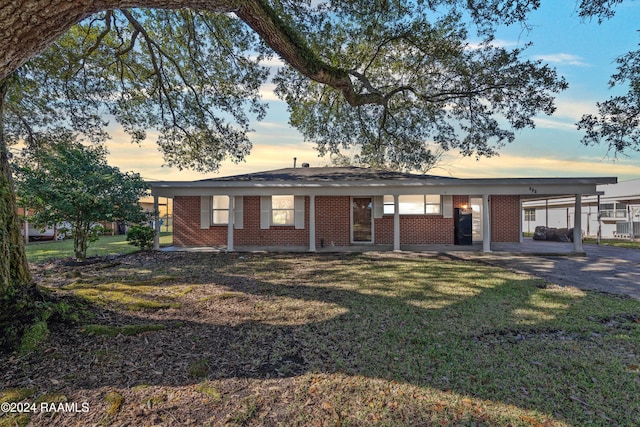 ranch-style home featuring a carport and a yard