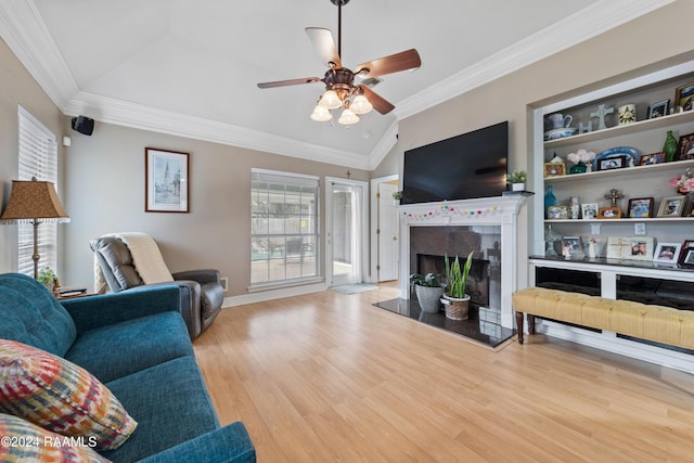 living room featuring a high end fireplace, light hardwood / wood-style flooring, vaulted ceiling, and crown molding