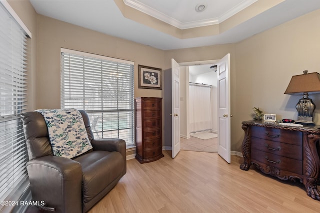 sitting room with light hardwood / wood-style floors, crown molding, and a tray ceiling