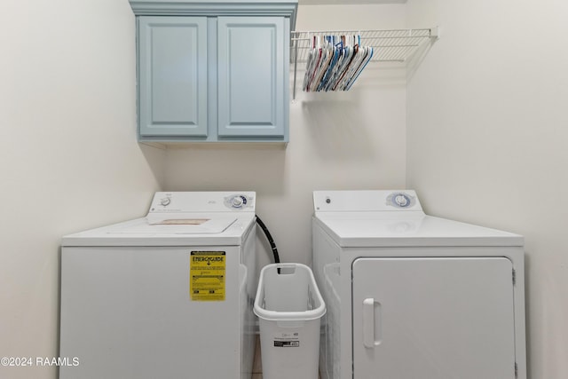 clothes washing area with cabinets and washing machine and clothes dryer