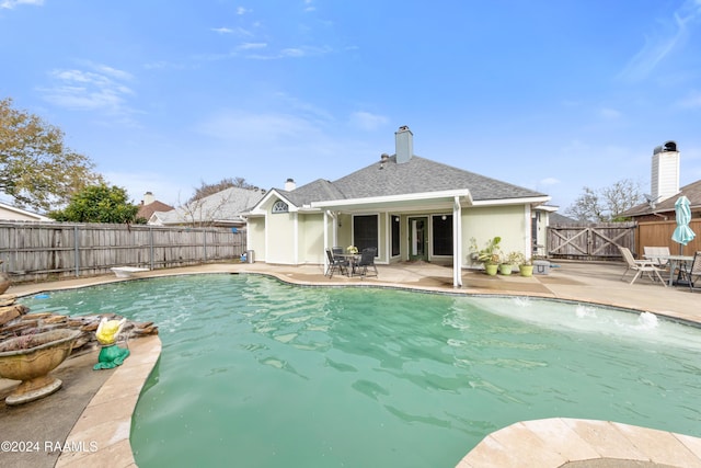 view of swimming pool with pool water feature, a diving board, and a patio