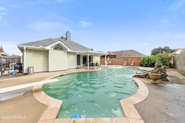 view of swimming pool with a diving board and a patio area