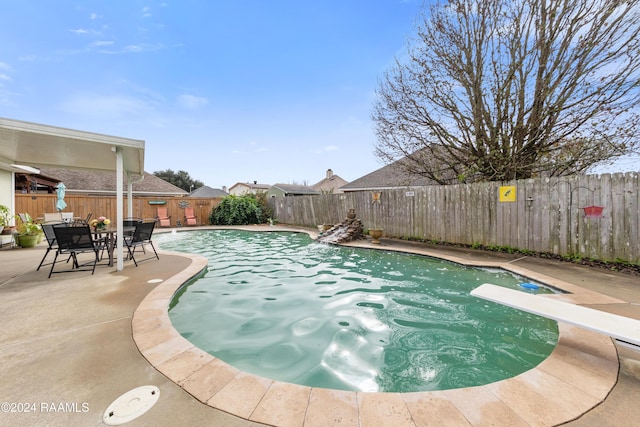 view of pool with a diving board and a patio area