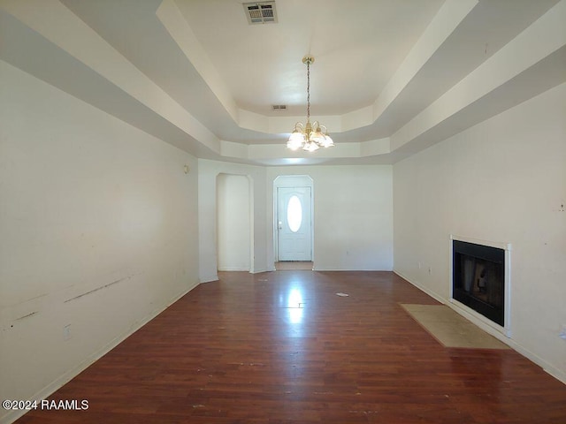 entryway with a raised ceiling, a chandelier, and dark hardwood / wood-style floors