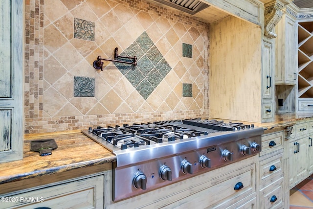 kitchen featuring light stone countertops, cream cabinets, tasteful backsplash, and stainless steel gas stovetop