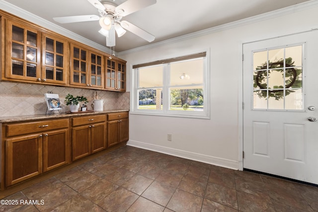 kitchen with decorative backsplash, ceiling fan, ornamental molding, and stone counters