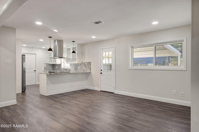 kitchen featuring pendant lighting, dark wood-type flooring, white cabinets, range hood, and kitchen peninsula