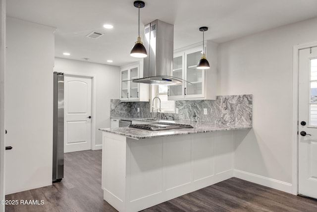 kitchen featuring light stone counters, backsplash, kitchen peninsula, island range hood, and white cabinets