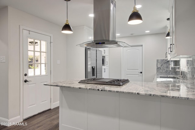 kitchen featuring kitchen peninsula, island range hood, white cabinetry, and light stone countertops