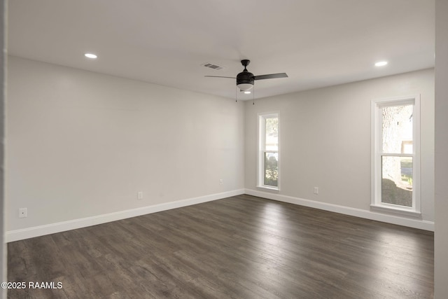 unfurnished room featuring ceiling fan, dark wood-type flooring, and a healthy amount of sunlight