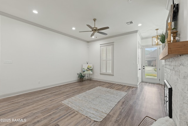 interior space featuring a fireplace, hardwood / wood-style floors, ceiling fan, and crown molding