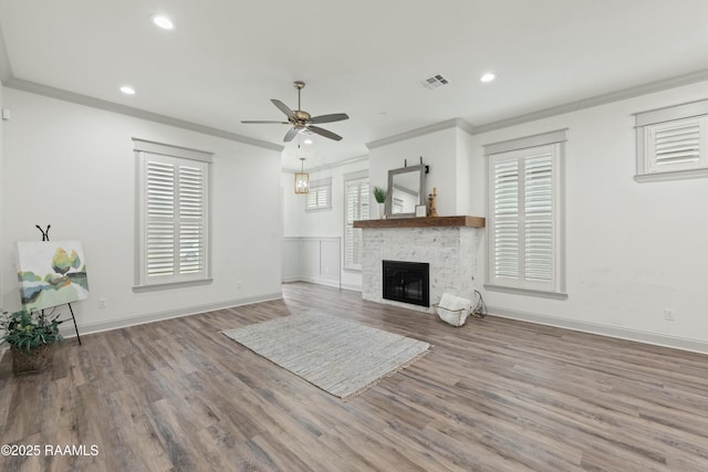 unfurnished living room with hardwood / wood-style flooring, ceiling fan, ornamental molding, and a fireplace