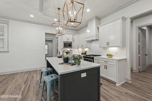 kitchen with stainless steel appliances, white cabinetry, a kitchen island with sink, and custom exhaust hood