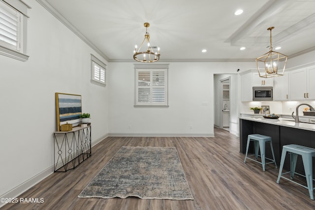 kitchen featuring stainless steel microwave, dark hardwood / wood-style flooring, white cabinetry, a breakfast bar area, and a chandelier