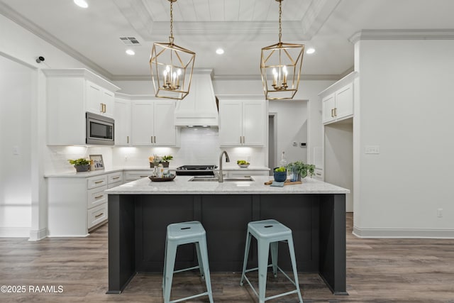 kitchen with white cabinets, custom exhaust hood, sink, and appliances with stainless steel finishes