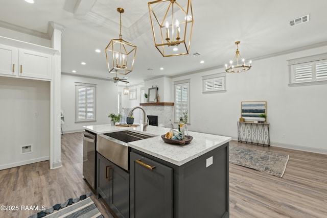 kitchen with decorative light fixtures, a center island with sink, a brick fireplace, and sink