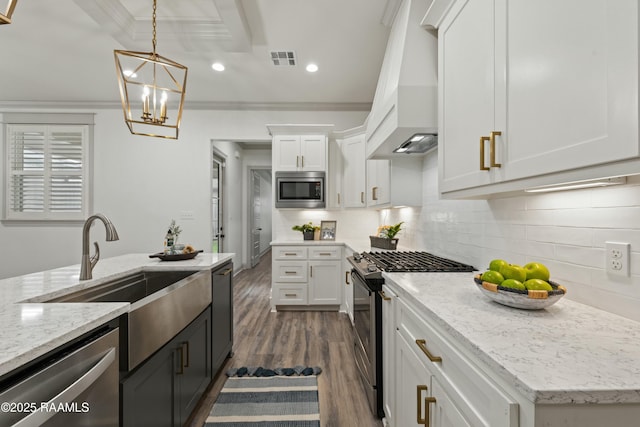 kitchen with sink, stainless steel appliances, a chandelier, white cabinets, and ornamental molding