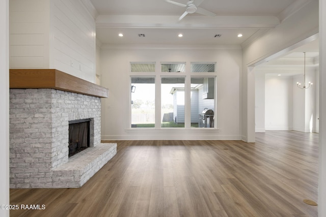 unfurnished living room featuring hardwood / wood-style flooring, ceiling fan with notable chandelier, ornamental molding, and a brick fireplace