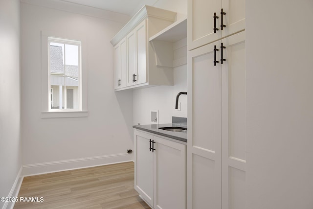 washroom with washer hookup, cabinets, light wood-type flooring, and sink