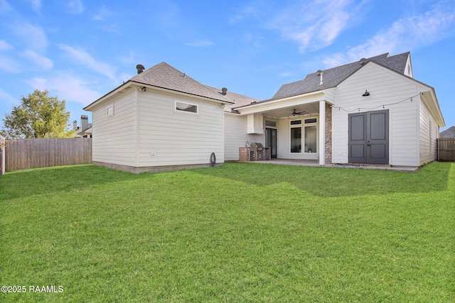 rear view of property with a lawn and ceiling fan