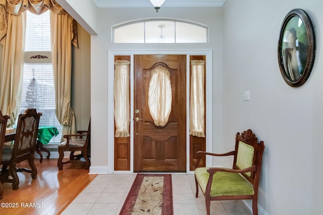 foyer with crown molding and light tile patterned floors