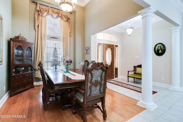 tiled dining area with an inviting chandelier, ornamental molding, and decorative columns