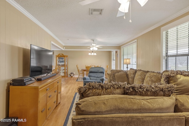 living room with ceiling fan, light hardwood / wood-style floors, a textured ceiling, and ornamental molding