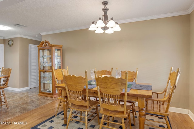 dining area with a chandelier, light wood-type flooring, and ornamental molding