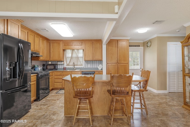 kitchen featuring a breakfast bar area, a wealth of natural light, a center island, and black appliances