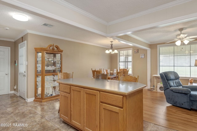 kitchen featuring a center island, hanging light fixtures, a textured ceiling, ceiling fan with notable chandelier, and ornamental molding