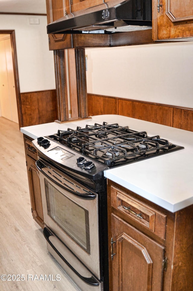 kitchen with stainless steel range with gas cooktop, range hood, and light hardwood / wood-style floors