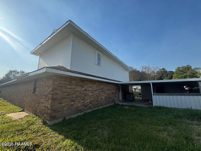 view of side of home featuring a yard, cooling unit, and a carport