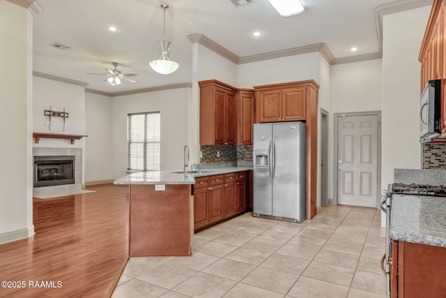 315 Begnaud Dr, Lafayette, LA 70501 - kitchen featuring appliances with stainless steel finishes, sink, kitchen peninsula, a tiled fireplace, and light tile patterned flooring