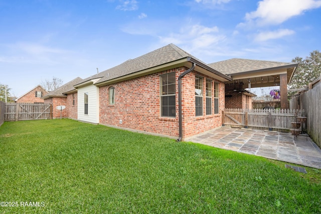 rear view of property with ceiling fan, a patio area, and a lawn