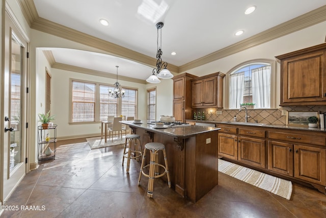 kitchen with sink, hanging light fixtures, a notable chandelier, a kitchen island, and a kitchen bar