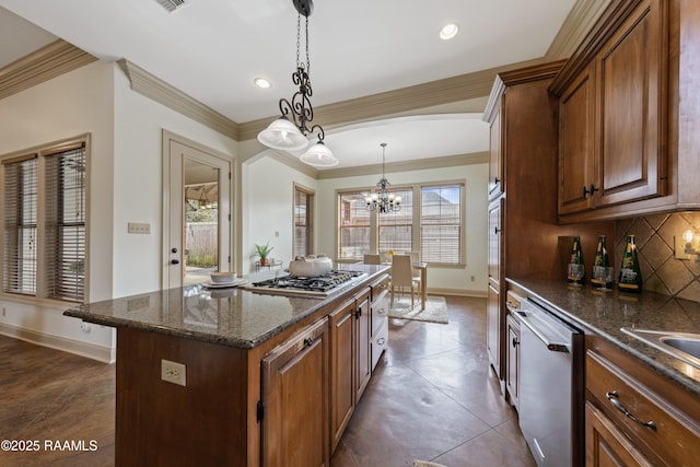 kitchen featuring stainless steel appliances, crown molding, decorative light fixtures, an inviting chandelier, and a kitchen island