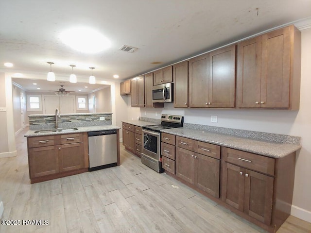 kitchen with light stone countertops, stainless steel appliances, ceiling fan, sink, and light hardwood / wood-style floors