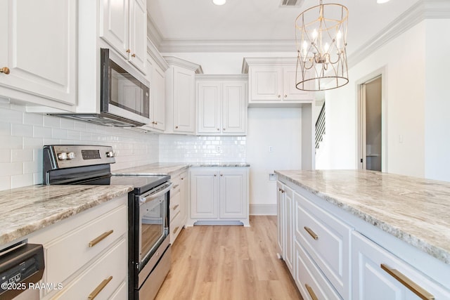 kitchen featuring pendant lighting, white cabinetry, appliances with stainless steel finishes, and an inviting chandelier