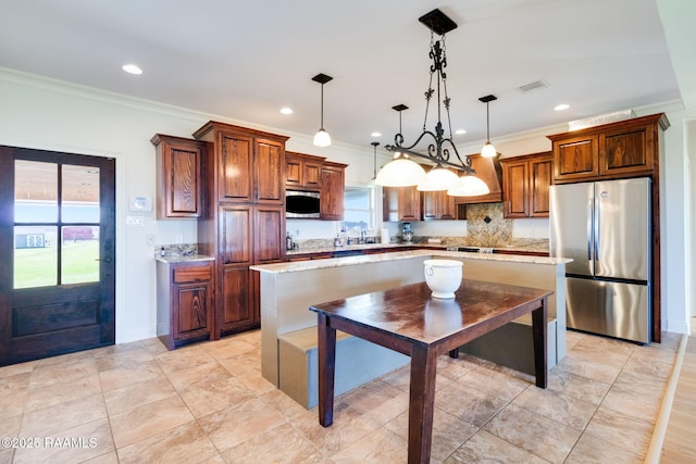 kitchen with pendant lighting, a center island, stainless steel appliances, and crown molding