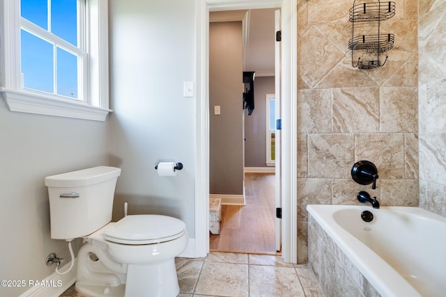 bathroom with tile patterned flooring, toilet, and tiled shower / bath