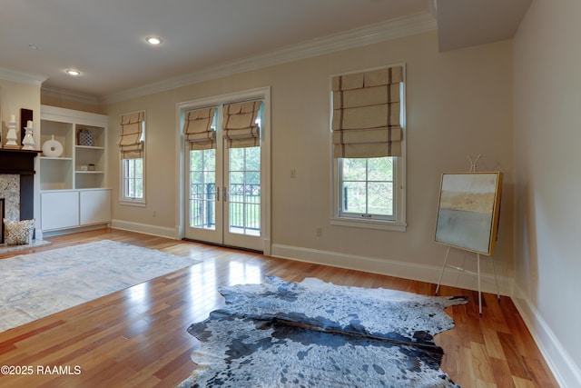 doorway to outside featuring built in shelves, a premium fireplace, light hardwood / wood-style flooring, and french doors