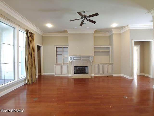 unfurnished living room with hardwood / wood-style floors, plenty of natural light, ornamental molding, and a tiled fireplace