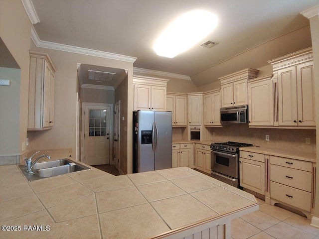 kitchen with cream cabinetry, appliances with stainless steel finishes, tile counters, and sink