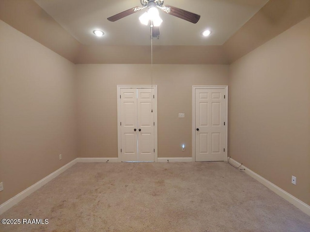 carpeted spare room with ceiling fan and vaulted ceiling