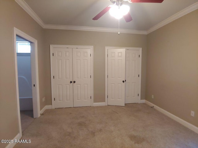 unfurnished bedroom featuring multiple closets, ceiling fan, light carpet, and ornamental molding