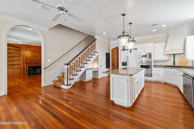 kitchen with hanging light fixtures, white cabinetry, a center island, and built in appliances