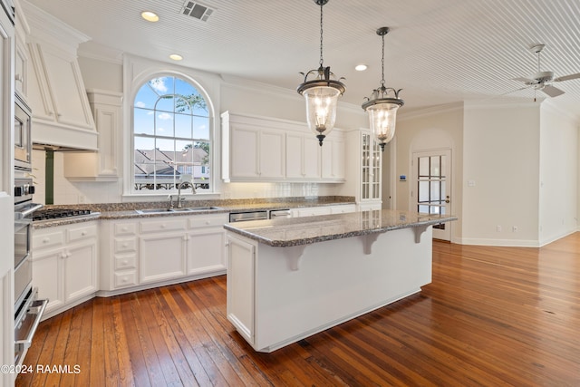 kitchen featuring sink, stone counters, dark hardwood / wood-style floors, white cabinets, and a kitchen island