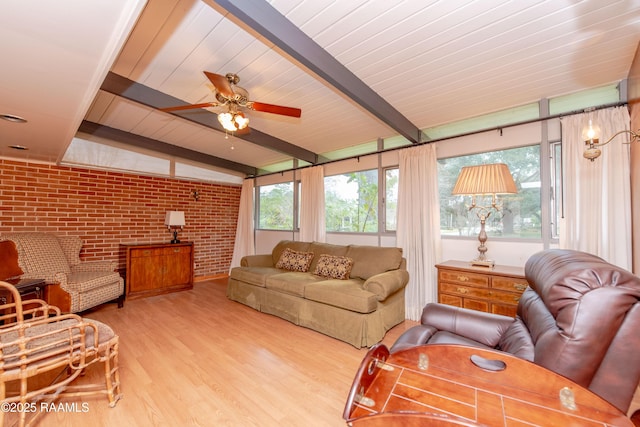 living room with light wood-type flooring, lofted ceiling with beams, ceiling fan, and brick wall